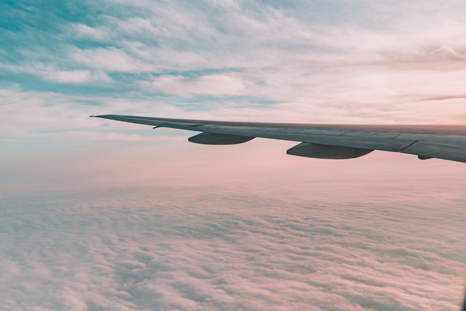 Airplane wing above sunset clouds at dusk